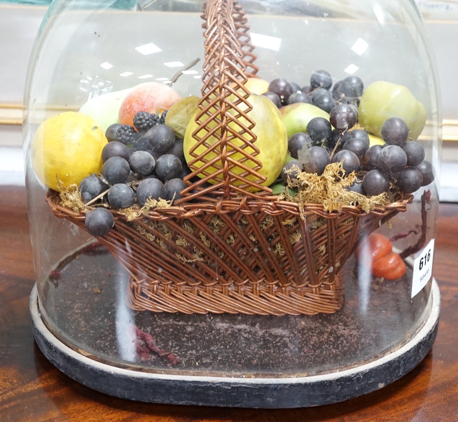 A Victorian wax fruit arrangement in a basket under glass dome, 34cms high